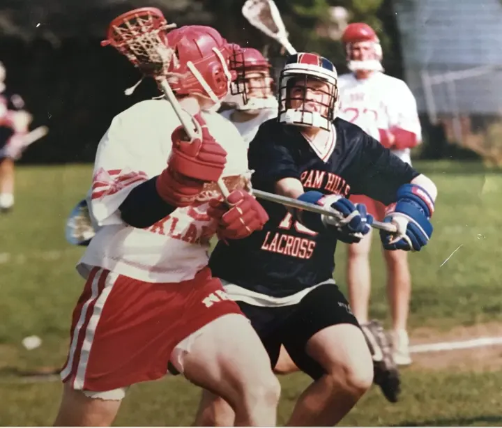 Two lacrosse players competing for position during a game.